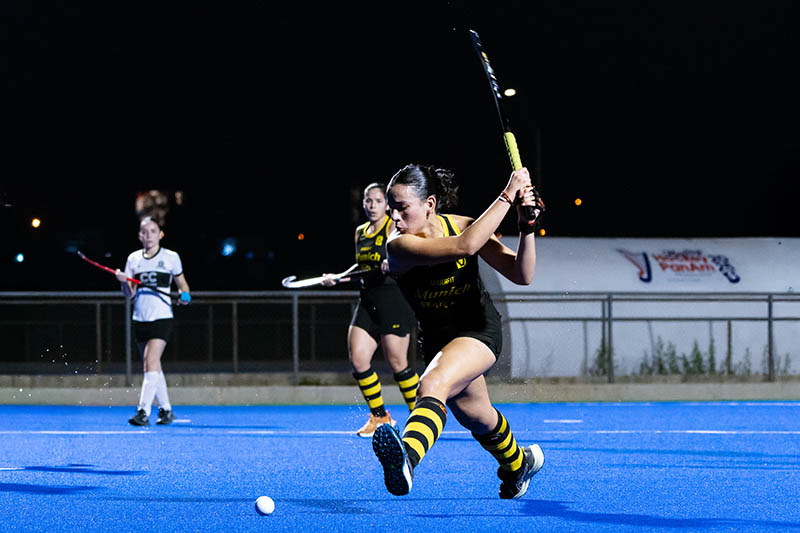 Un buen entrenamiento de hockey sobre césped no se limita a pegarle a la bocha. Para rendir en el partido hay que trabajar cuatro áreas a la vez: técnica, táctica, preparación física y el aspecto psicológico-social. Si entrenás solo una, el resto del juego se resiente. Las 4 áreas del entrenamiento de hockey Técnica. Es la base de todo jugador. Incluye el control de la bocha (por derecho y por revés), las conducciones, los driblings, los amagues, la recepción, el pase y la definición a portería. Táctica. Aquí se trabaja la inteligencia de juego: posicionamiento en el campo, superioridades e inferioridades numéricas (como el clásico 3 vs 1), transiciones rápidas y juegos reducidos. Preparación física. Comprende fuerza máxima, potencia, fuerza rotacional, tren inferior y glúteos, además de velocidad, agilidad, pliometría y capacidad aeróbica y anaeróbica. Gran parte de este trabajo se puede hacer con el palo y la bocha en la mano, para que el físico se entrene en situaciones parecidas al juego. Psicológica y social. Tomar decisiones bajo presión, mantener la concentración y construir cohesión de equipo es lo que inclina los partidos parejos. Cómo estructurar una sesión de entrenamiento de hockey Una sesión de unos 85 a 90 minutos puede organizarse así: Entrada en calor (15-20 min): movilidad articular, trote dinámico y activación muscular con fuerza básica, como lagartijas o pliometría ligera. Técnica individual (20 min): slalom entre conos, conducción con una y dos manos (derecho y revés) y regates como el regate en V. Situaciones tácticas y juegos reducidos (25 min): espacios acotados, por ejemplo 3 vs 3 en 15 x 30 metros, para trabajar posesión, pase y definición rápida. Definición o jugadas específicas (15 min): tiros al arco, pelotas paradas o trabajo por puesto (delanteras, mediocampistas, defensoras y arqueras). Vuelta a la calma (10 min): estiramientos y charla táctica de cierre. Ejercicios prácticos para mejorar el control y la conducción de la bocha Slalom entre conos: conducí la bocha en zigzag cuidando el contacto constante con el palo. Empezá a ritmo lento y subí la velocidad de a poco. Conducción con una y con dos manos: alterná ambas formas en recta y en curva. Es clave para ganar soltura y protección de la bocha. Derecho y revés: repetí el recorrido en los dos sentidos para que el revés deje de ser tu punto débil. Regate en V: llevá la bocha hacia afuera y recuperala hacia adentro en forma de V para driblar a un rival con rapidez. Juegos reducidos 3 vs 3: combinan control, pase y definición bajo presión real de marca. Consejos para sacarle más provecho a cada entrenamiento Trabajá siempre ambos lados (derecho y revés). Aumentá la dificultad de forma progresiva: primero precisión, después velocidad, por último presión de un rival. Integrá la preparación física con el palo y la bocha siempre que puedas. Cerrá cada sesión con una breve charla para repasar qué funcionó y qué corregir. Un entrenamiento de hockey bien planificado, constante y equilibrado entre las cuatro áreas es lo que marca la diferencia entre jugar y rendir.